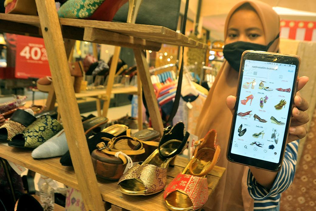 Ilustrasi pelaku UMKM mengemas produk dan memasarkan barang melalui marketplace menggunakan smartphone.